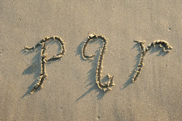 Алфавитные буквы, написанные от руки песком на пляже — стоковое фото
