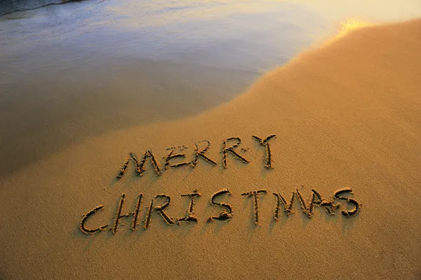 Merry Christmas handwritten in sand on beach — Stock Photo, Image