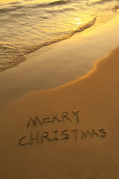 Merry Christmas handwritten in sand on beach — Stock Photo, Image