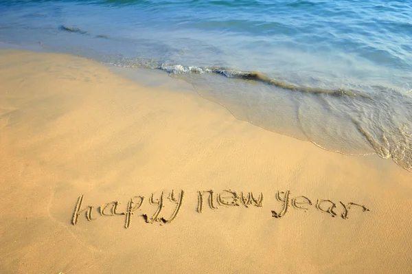 Gelukkig nieuw jaar geschreven in het zand — Stockfoto
