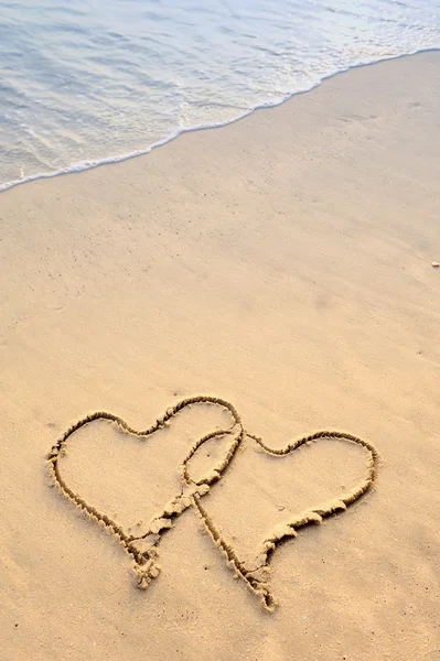 Dois corações desenhados na areia de uma praia — Fotografia de Stock