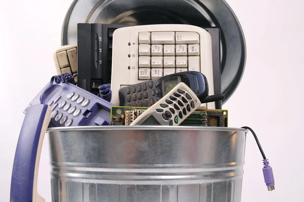 Различные компьютерные детали и телефон в мусорном баке — стоковое фото