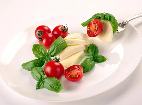 Моцарелла с помидорами и базиликом на вилке — стоковое фото