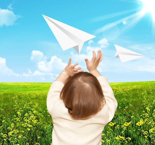 Den små flickan spelar med pappersflygplan — Stockfoto