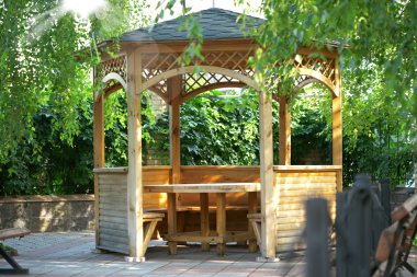 Wooden summerhouse is in park clipart