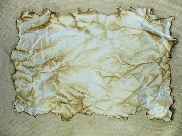 Aged crumpled burned paper over canvas — Stock Photo, Image