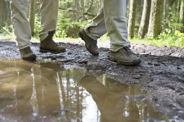 泥の水たまりを歩くハイカー — ストック写真