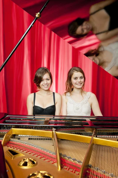 Vackra flickor spela två del harmoni på ett piano — Stockfoto