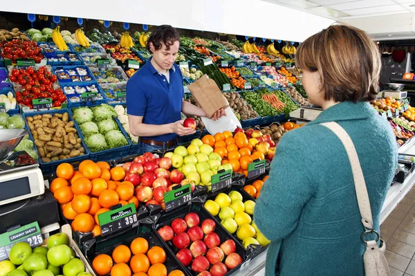 Greengrocer обслуживает клиентов — стоковое фото