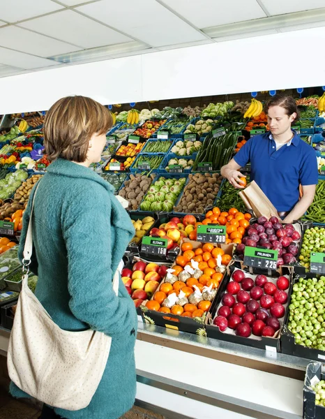 Gemüsehändler bedient einen Kunden — Stockfoto