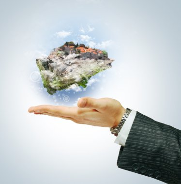 Flying island on businessman's hand clipart