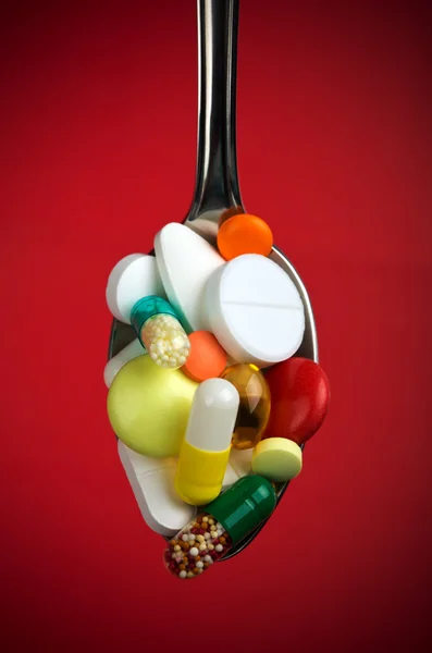 Ложка, наповнена різними таблетками — стокове фото
