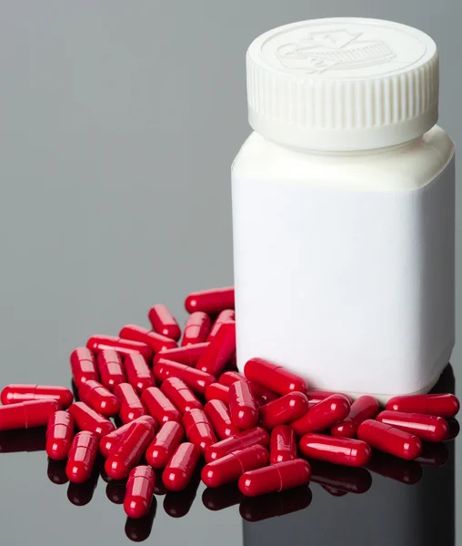 Pílulas vermelhas e garrafa — Fotografia de Stock