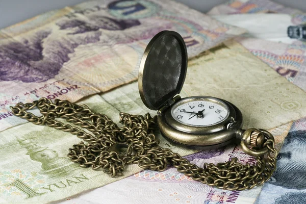 Часы с цепью и деньгами — стоковое фото