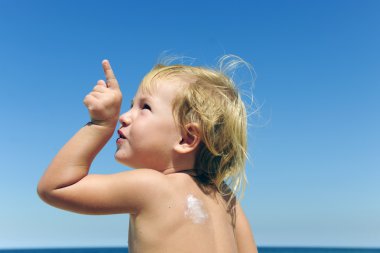 Cute child with sunscreen at the beach clipart