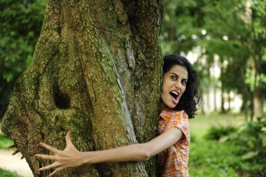 In love with nature: woman hugging a tree in the forest clipart