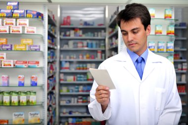 Pharmacist reading prescription at pharmacy clipart