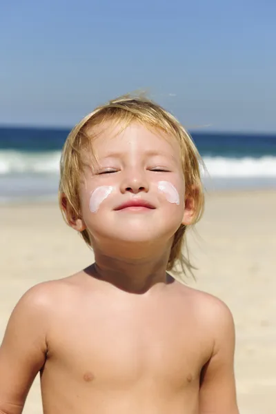 Söta barn med solskydd på stranden — Stockfoto