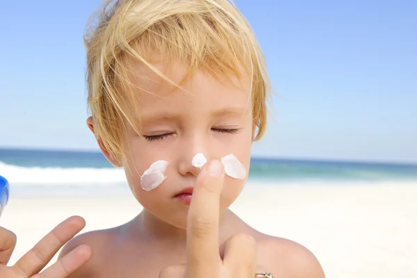 Мила дитина з сонцезахисним кремом на пляжі — стокове фото