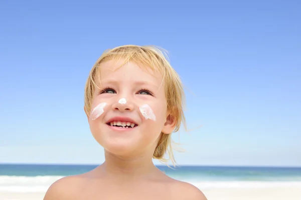 Criança bonito com protetor solar na praia — Fotografia de Stock