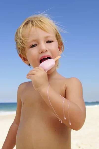 Літня відпустка: дитина їсть айсберг на пляжі — стокове фото