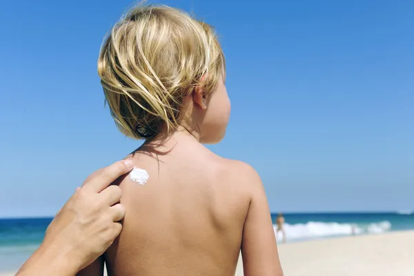 Mor tillämpa solskyddsmedel på barn — Stockfoto