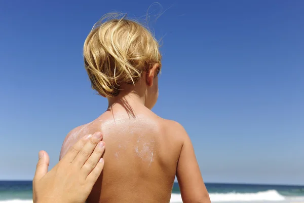 Mutter trägt Sonnencreme auf den Rücken der Kinder auf — Stockfoto