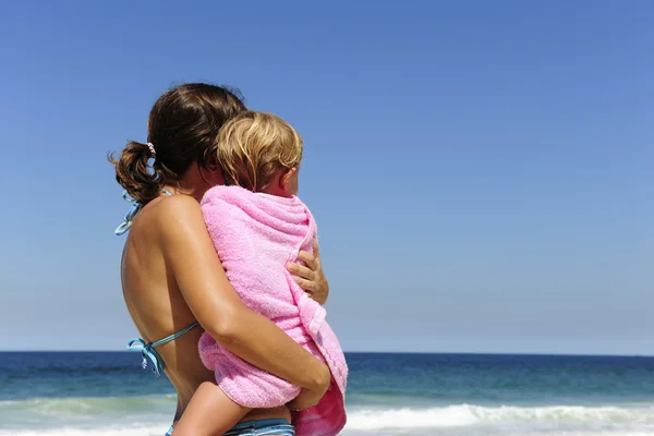 Мать несет свою дочь на пляже — стоковое фото