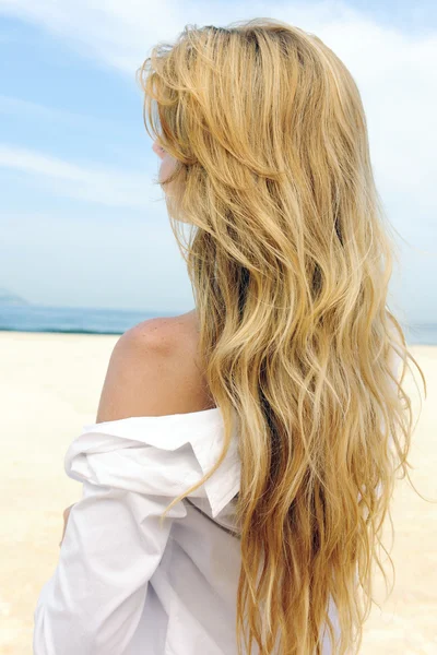 Elegancka kobieta z długimi blond włosami na plaży — Zdjęcie stockowe