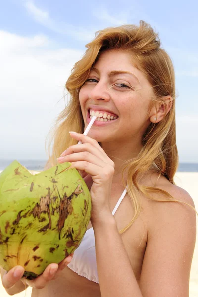 Жаждущая женщина пьет кокосовую воду на пляже — стоковое фото