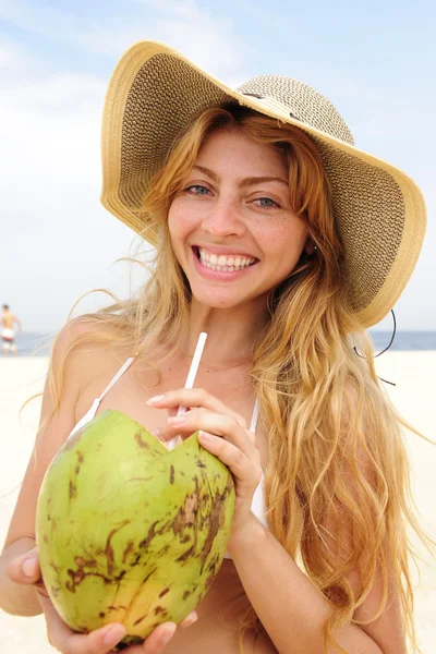 Жага жінка п'є кокосову воду на пляжі — стокове фото