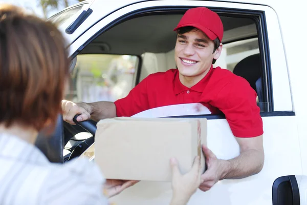 Postal delivery courier in a van delivering package — Stock Photo, Image