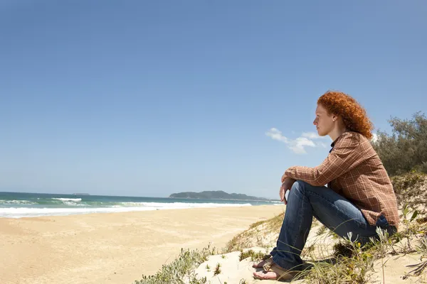Eftertänksam kvinna sitter på sanddynerna — Stockfoto