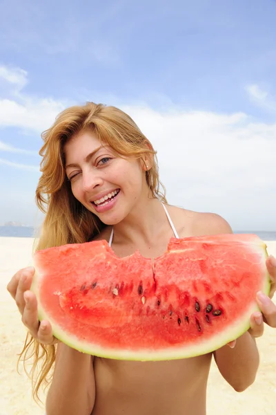 Vrouw die watermeloen eet op het strand Stockfoto