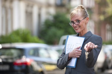 Female Real Estate Agent holding house key clipart