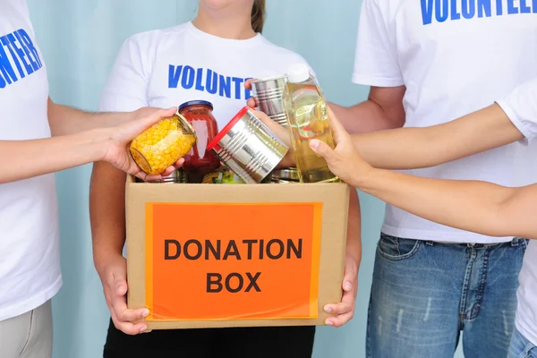 Добровольцы кладут еду в коробку для пожертвований — стоковое фото