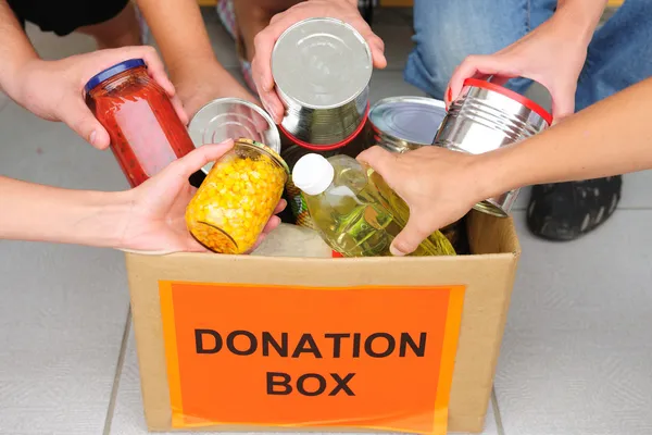 Voluntários colocando comida em caixa de doação — Fotografia de Stock