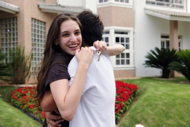 Couple standing outside new house clipart