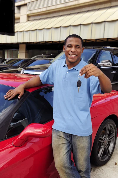 Uomo che mostra la chiave della nuova auto sportiva rossa — Foto Stock