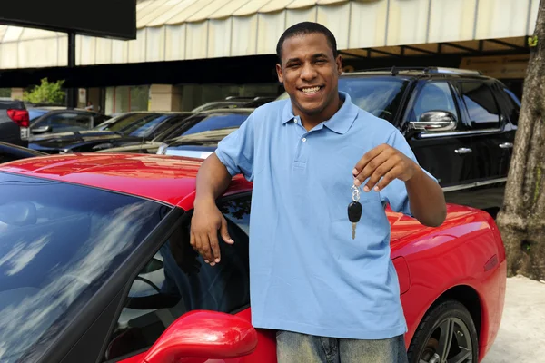 Чоловік показує ключ нового червоного спортивного автомобіля — стокове фото