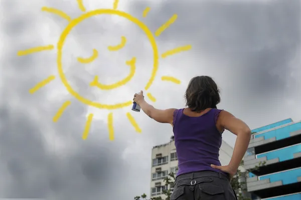 Frau malt die Sonne in den bewölkten Himmel — Stockfoto