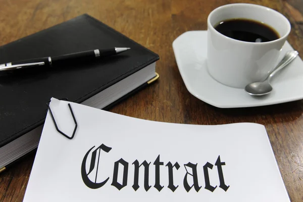 Kontrakt och kaffe på ett skrivbord — Stockfoto