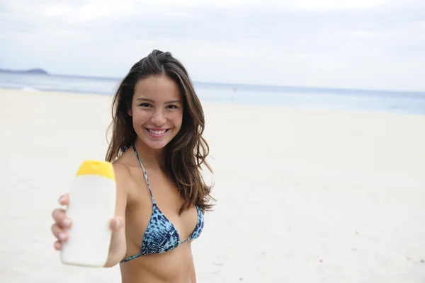 Жінка показує сонцезахисний крем на пляжі — стокове фото