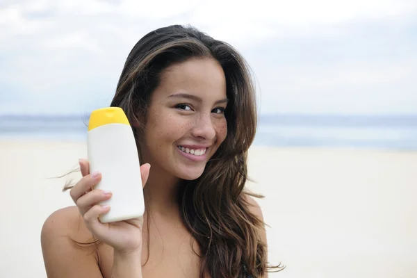 Woman showing suncream at the beach — Stock Photo, Image