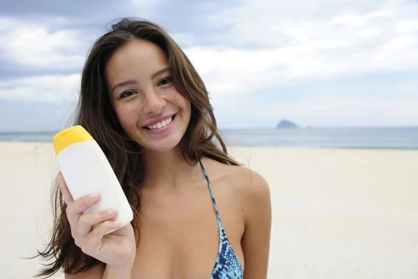 Mujer mostrando crema solar en la playa —  Fotos de Stock