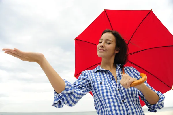 Женщина с красным зонтом дотрагивается до дождя — стоковое фото