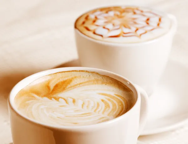 Kaffeetasse mit kunstvoller Cremedekoration — Stockfoto