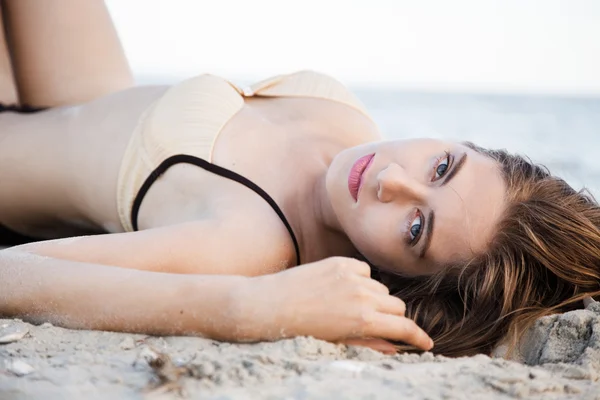 Модель, лежащая в песке — стоковое фото