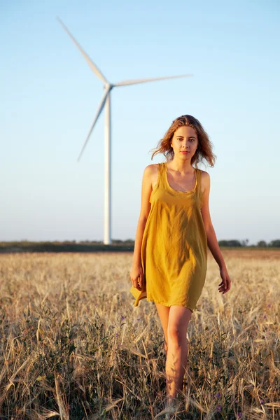 Signora che cammina nel campo con mulino a vento sullo sfondo — Foto Stock