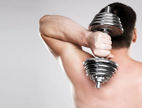 Athletic man lifting a dumbbell — Stock Photo, Image